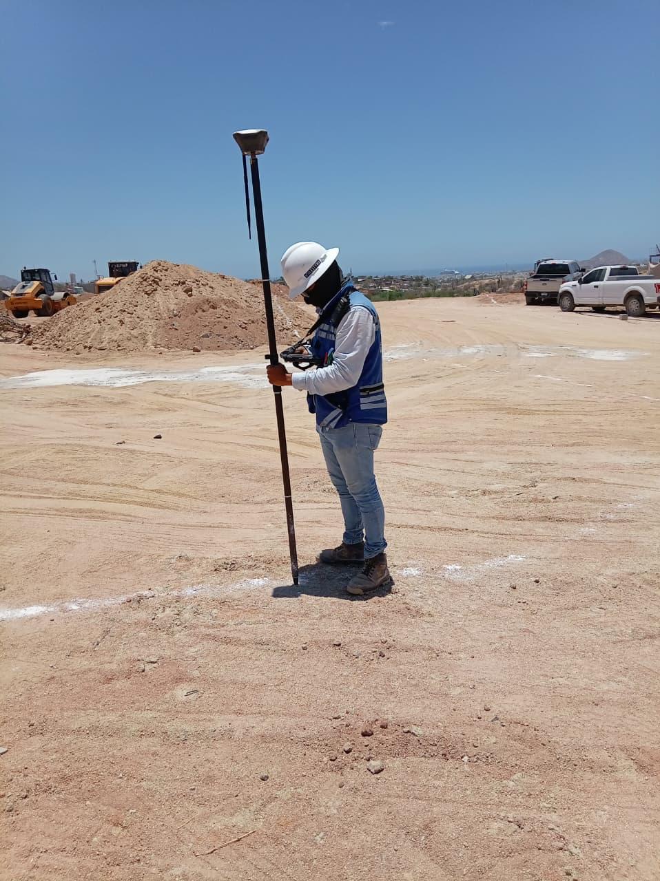 Técnico con casco y chaleco realizando un levantamiento GNSS en terracerías